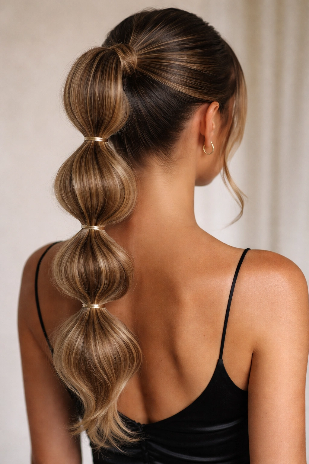 Back view of a bubble ponytail with evenly spaced elastics forming bubbles