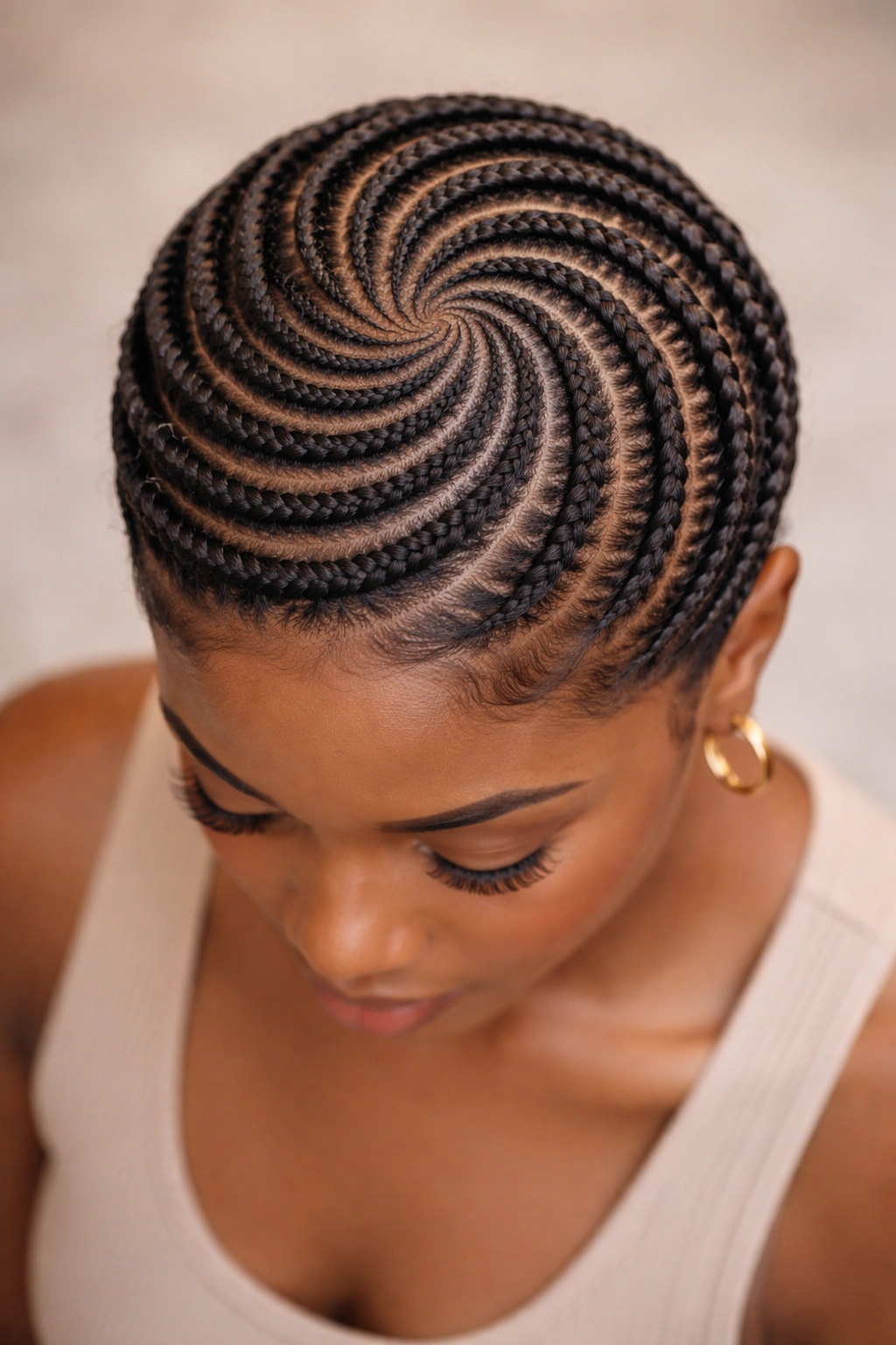 Circular cornrows forming a crown swirl on short natural hair.