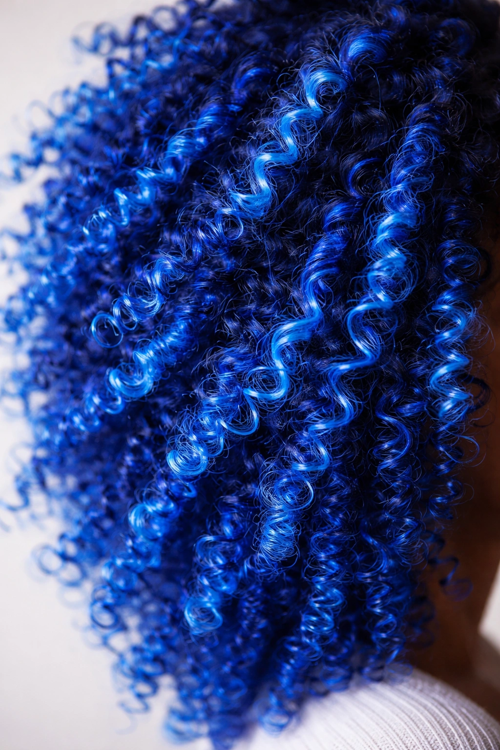 Close-up of electric blue coily hair glowing under light
