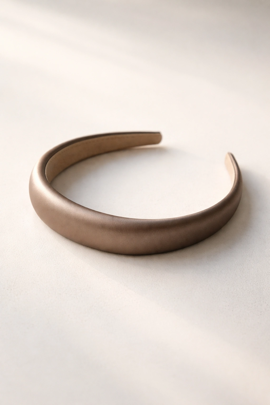 Minimalist still-life of a single sleek headband on a neutral surface