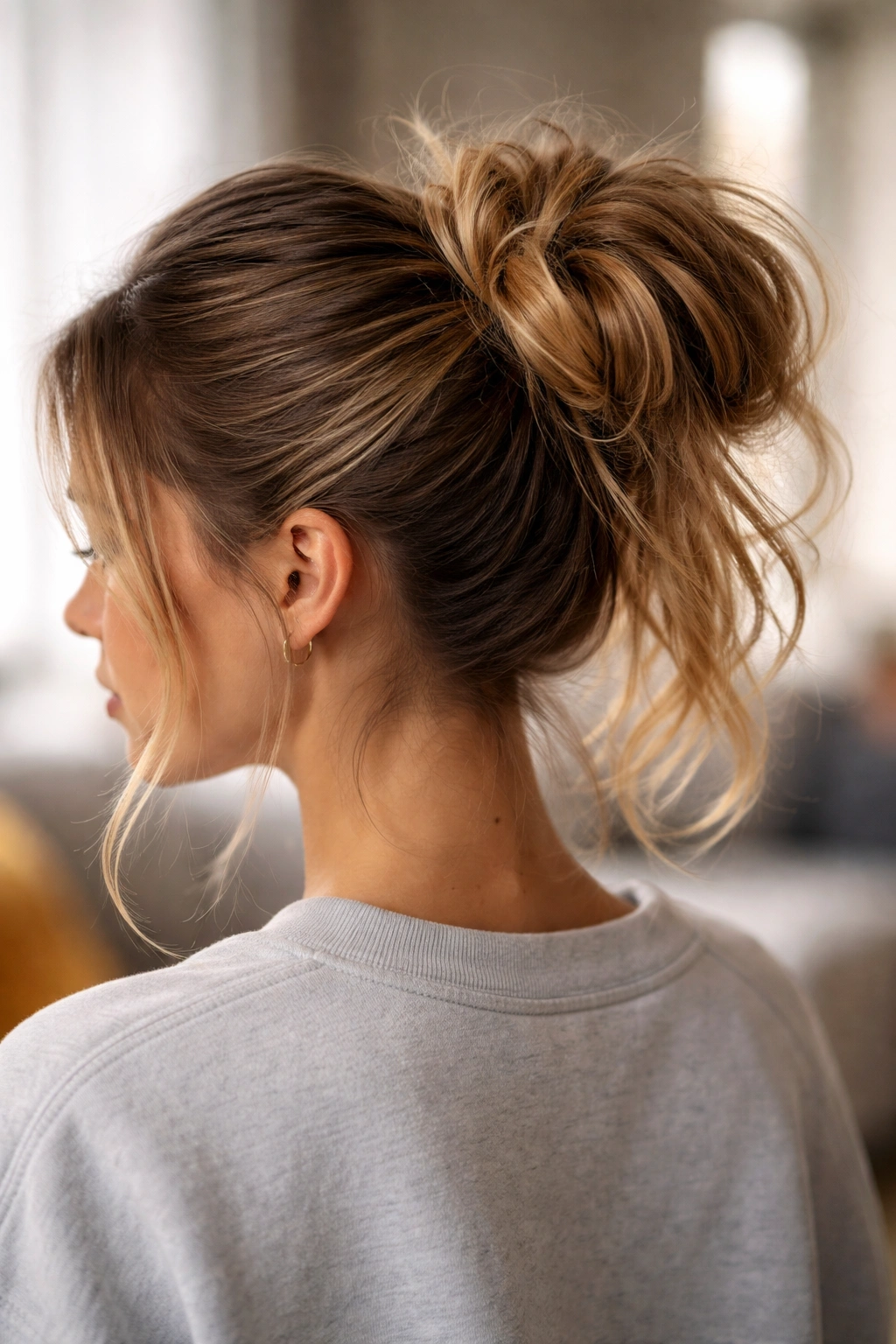 Messy bun ponytail with loose face-framing strands