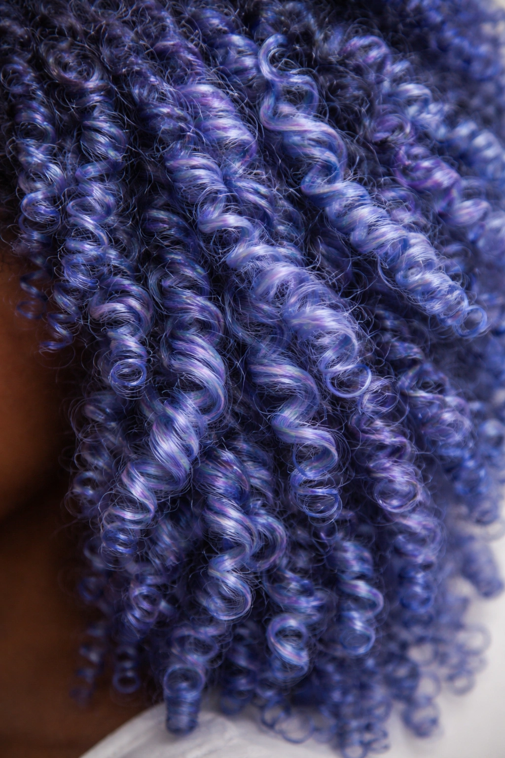 Close-up of periwinkle blue coily hair showing blue-purple shift in curls