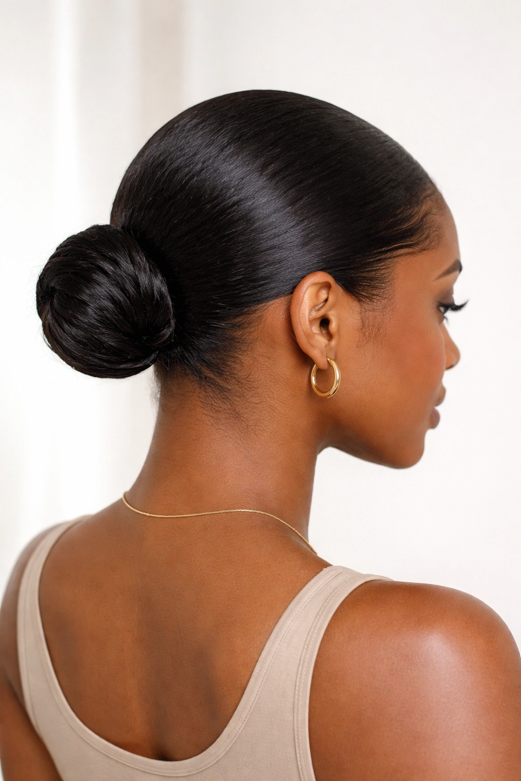 Back view of a sleek low bun at the nape with smooth coils