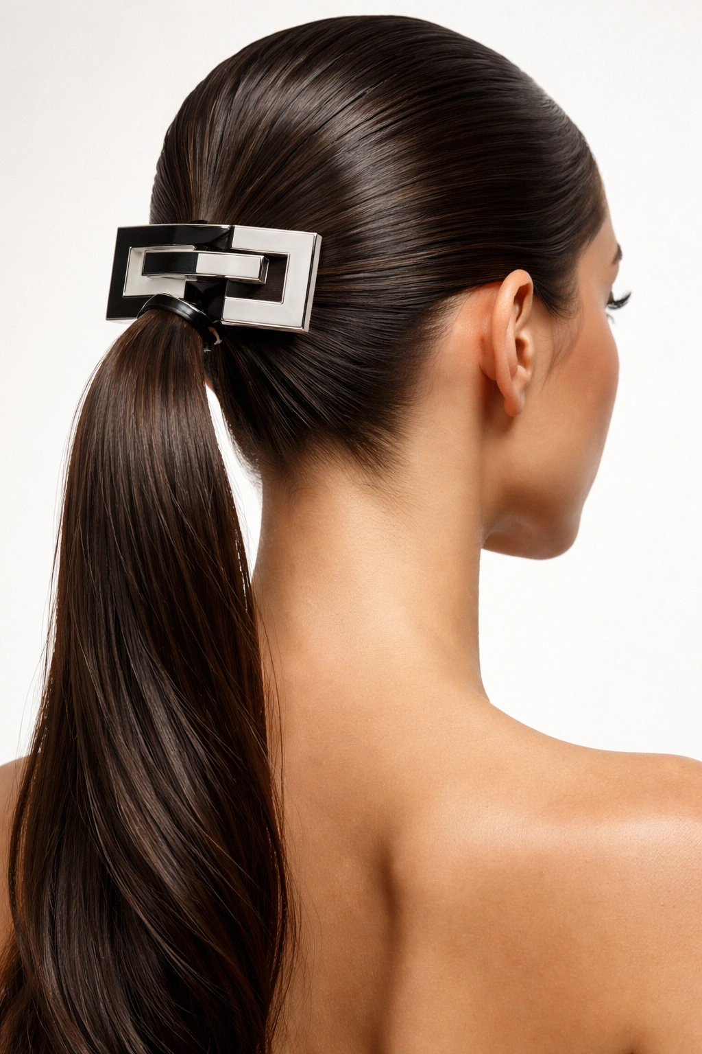 Slicked-back ponytail with bold graphic barrette in studio