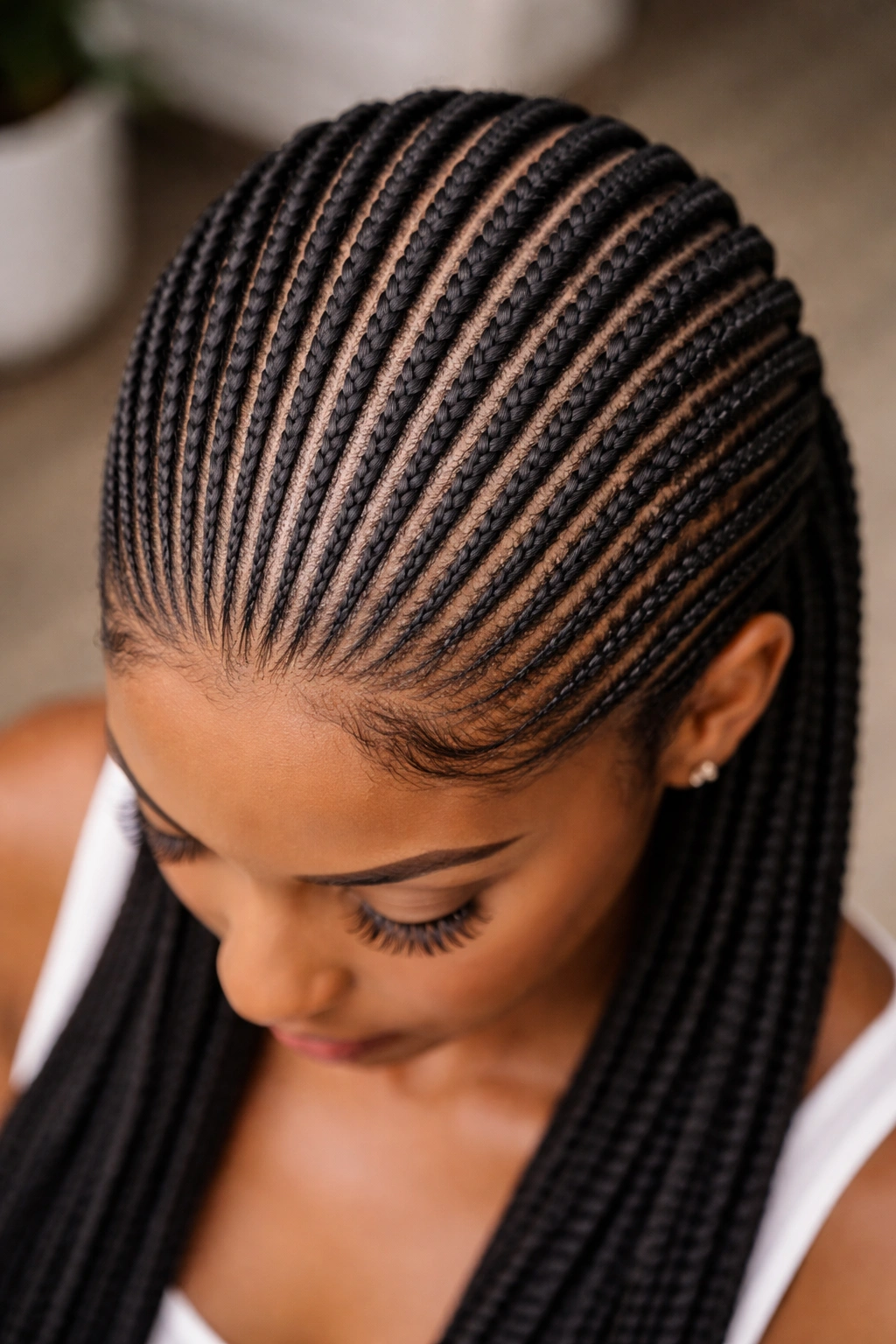 Overhead view of stacked feed-in cornrows forming dense parallel rows across the scalp
