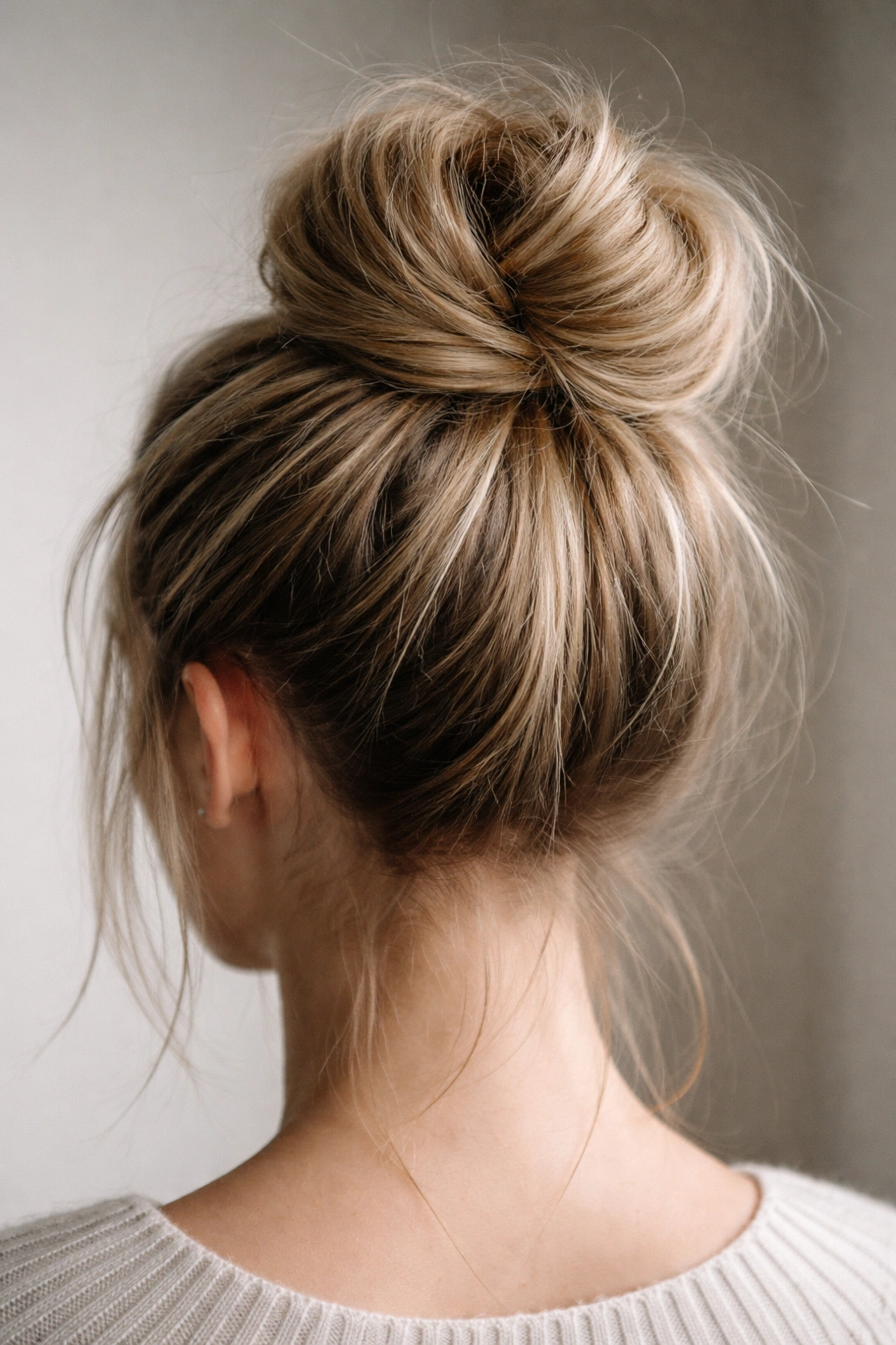 Close-up of a textured crown bun with backcombed roots on a neutral backdrop