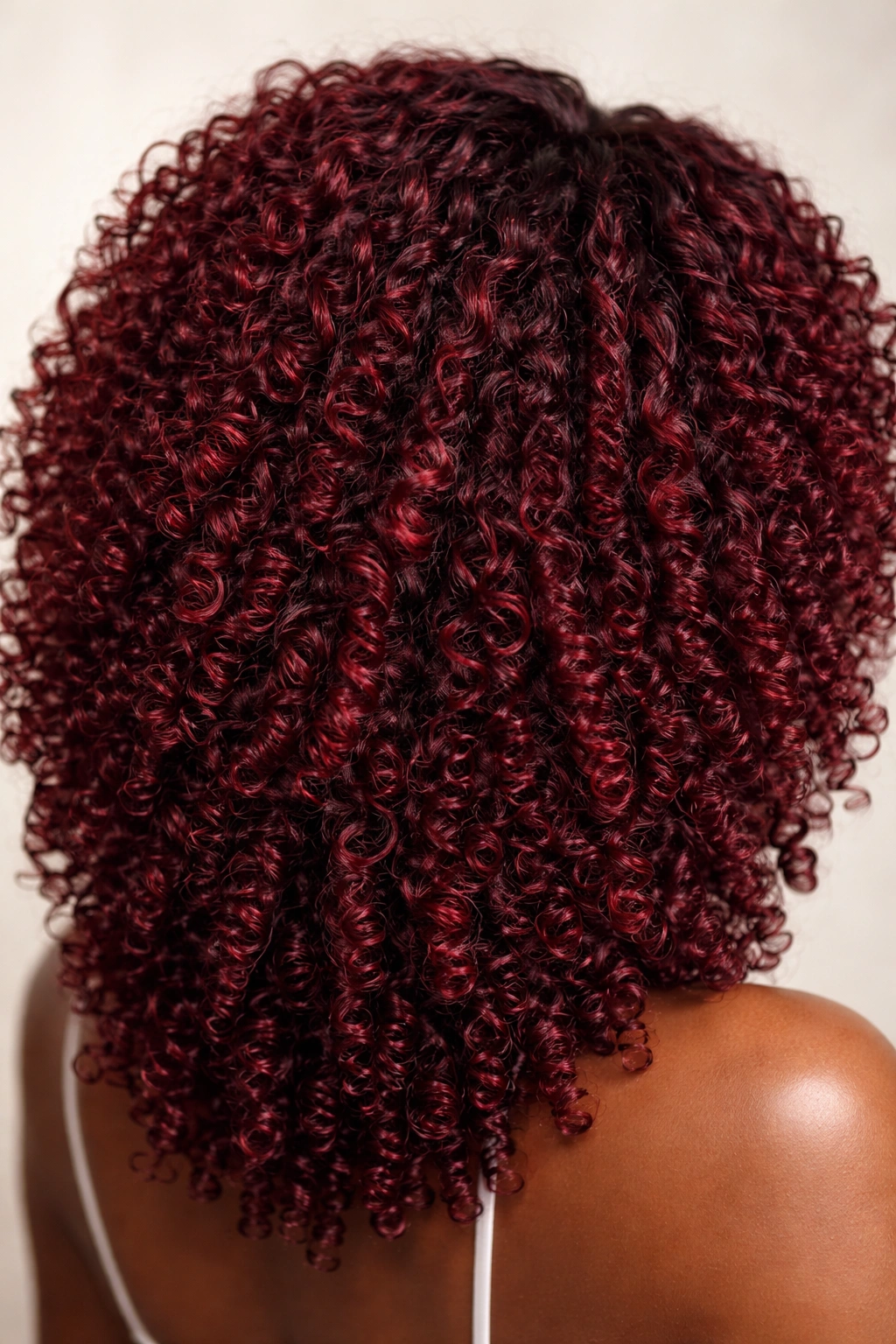 Close-up of coily hair in wine red with jewel-like depth