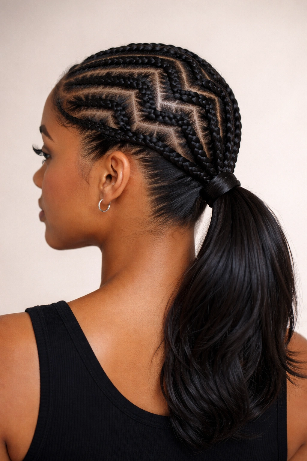 Three-quarter view showing zigzag cornrows converging into a low ponytail at the nape