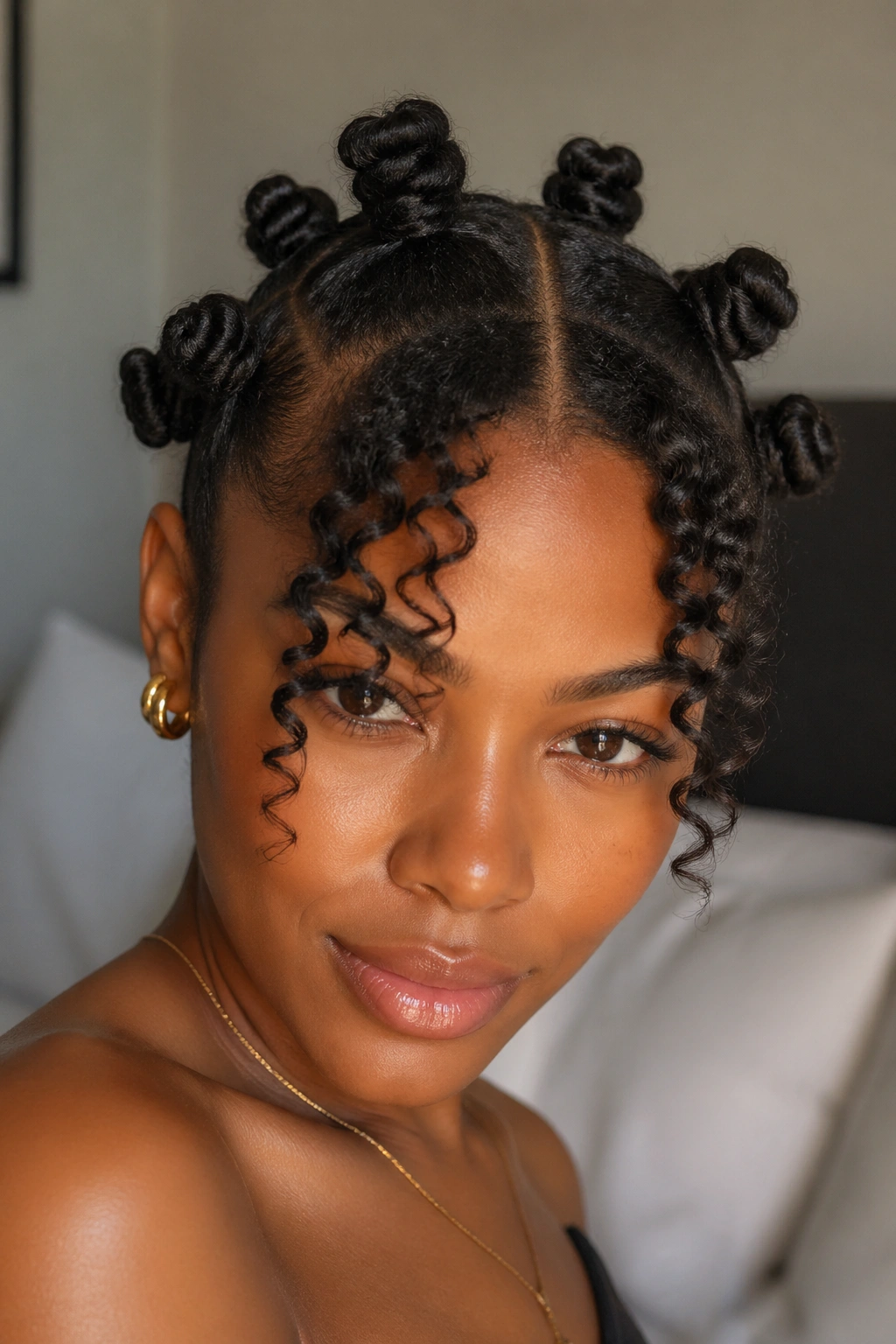 Close-up portrait of a woman with a center-part and bantu knot crown with curly bangs
