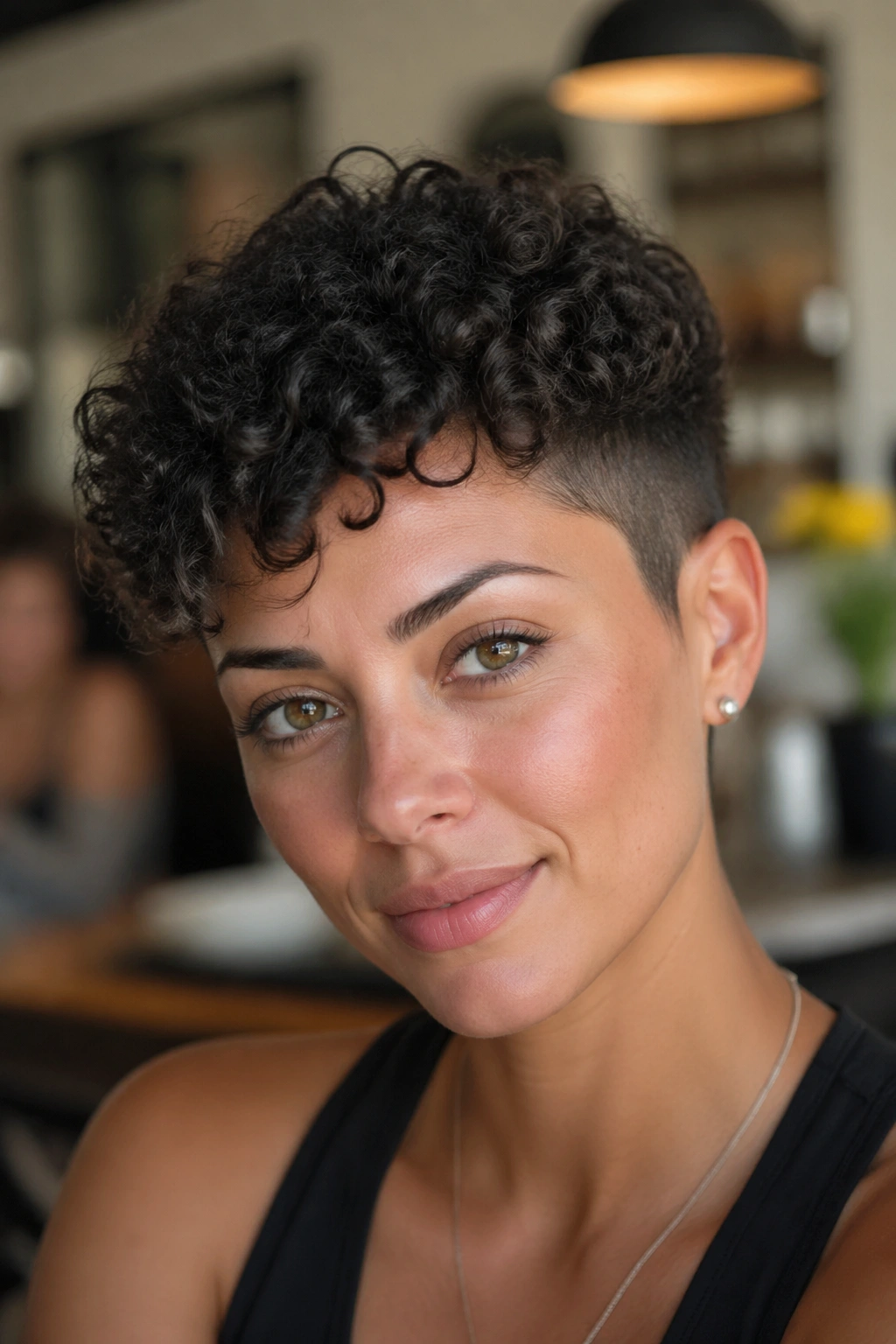 Close-up of a real person with a curly pixie haircut featuring tapered sides.