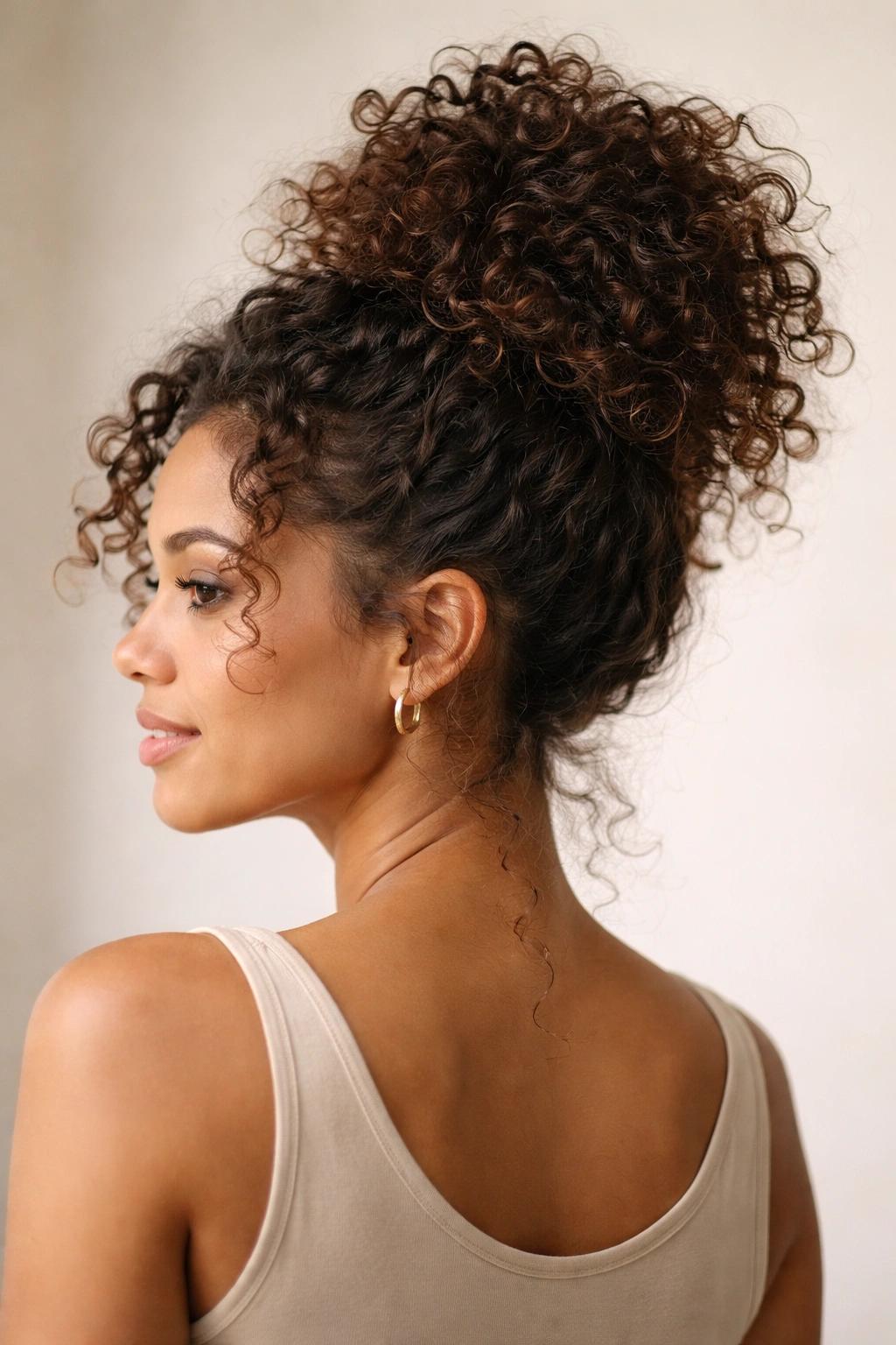 Close-up of a high crown pineapple messy bun on curly hair with curls spilling softly