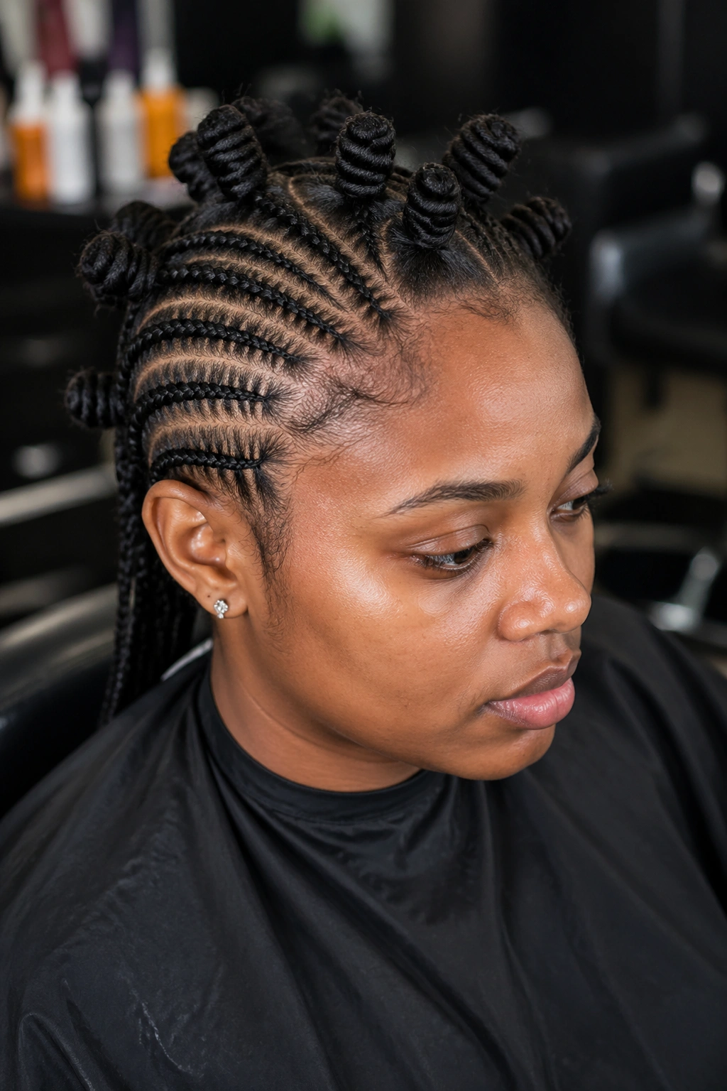 Medium close-up portrait of a person in a salon chair with neat scalp parts ready for stitch braids with Bantu knots