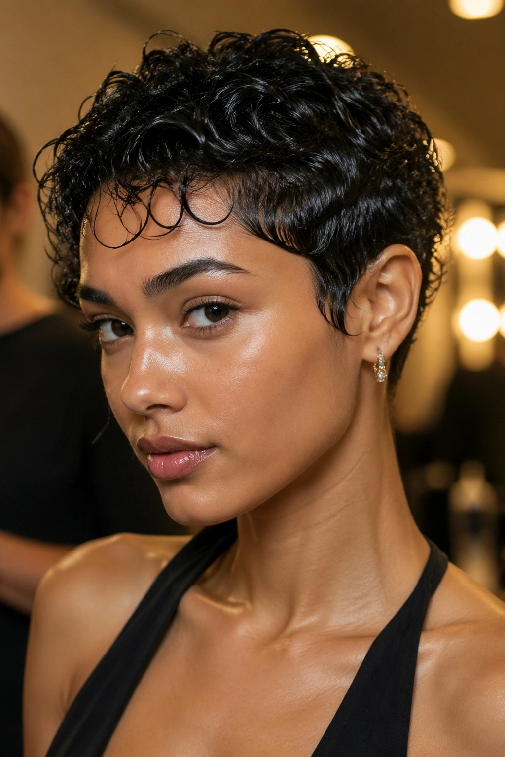 Close-up of a real person with a sleek wet-look curly pixie hairstyle