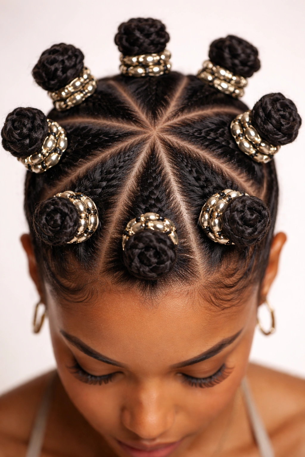 Close-up of triangle-part Bantu knots with metallic beads on scalp, studio lighting