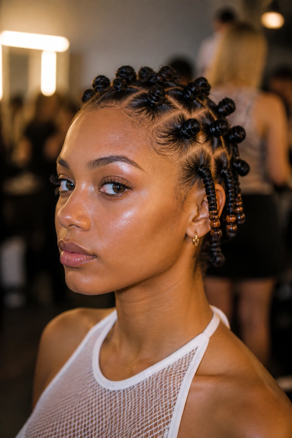 Close-up portrait of a real person with low-profile bantu knots with bead ends on a bob cut, beads at knot ends, backstage festival lighting