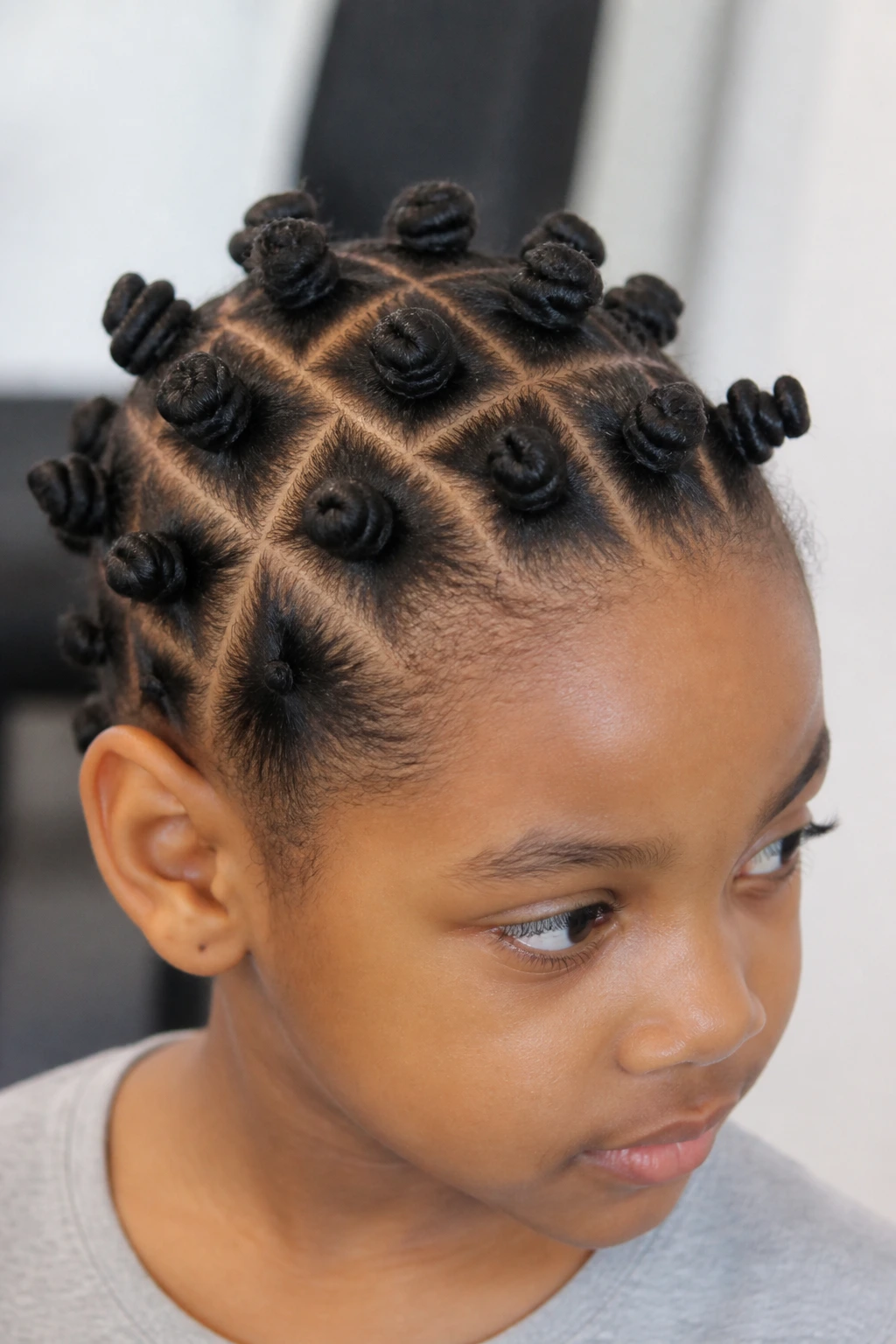 Close-up of a real child showing a grid-part bantu knot pattern on the scalp.